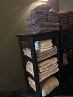 Stacks of folded towels and sheets on two shelf units, showing color variety