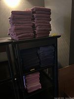 Stacked burgundy and navy towels on first dark shelving tower