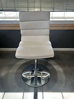 Front view of white faux leather bar stool showing seat, backrest, chrome base