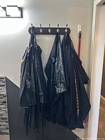 Four black salon/barber capes hanging on wall hooks