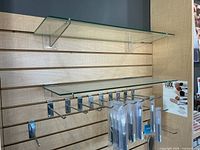 Slatwall panels with two glass shelves, chrome hooks and acrylic brackets attached