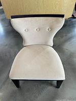 Front view of beige microfiber accent chair showing seat, button-tufted backrest, dark legs