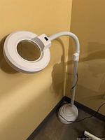 Full view of white LED magnifying floor lamp standing in corner