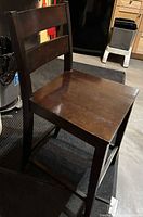 Front-left view of dark brown ladder back counter-height wooden chair showing seat scratches