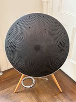 Front view of Bang & Olufsen Beoplay A9 speaker on light wood legs with power cord