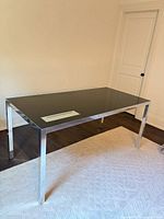 Front angled view of steel frame desk with glass top