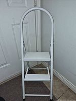 Front view of white 2-step folding ladder showing both steps and handle