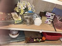 Shelved lot showing silk flowers, moss bags, floral foam boxes, styrofoam form, artificial fruit centerpiece, ceramic planter, totes
