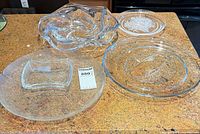 Four glass pieces grouped: wavy bowl, crackle platter with square dip bowl, floral plate, fish plate