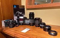 Group shot of camera, flash, three lenses, accessories and case displayed on wooden surface