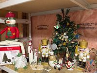 Shelf with boxed Ashland tree, plush snowman, decorated tabletop tree, nutcrackers, various figurines and ornaments