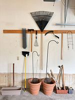 Wide view of all tools, pots, hooks and planters arranged on garage wall and floor