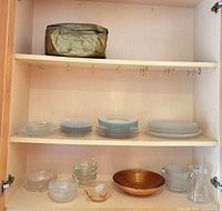 full cabinet view showing plates, bowls, copper bowl, ice bucket and carafe