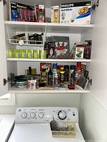 Cupboard shelves with bulb packs, aerosol cleaners, wax tins and tools