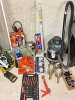 Overall view showing shop-vac, lanterns, stud finder, timers, extension cords, tool kit, flashlights and hardware