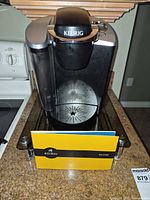 Front view of Keurig coffee machine on pod drawer with booklet visible