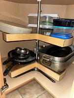 Overview of rotating cabinet shelves showing frying pans, steamer basket, roasting pans, assorted storage containers
