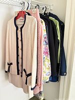Garments on hangers showing cream boucle suit, additional clothing behind