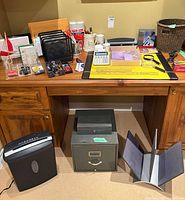 Overall lot showing desk surface with supplies, shredder, filing cabinet