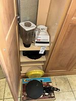 Cabinet view showing blender pieces, hot plate, waffle maker and crepe maker
