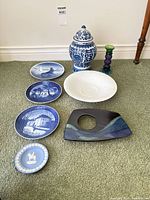 Group shot of all items: four Royal Copenhagen plates, ginger jar, Rosenthal plate, black tray, Wedgwood plate, candlestick