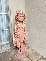 Full view of terracotta child statue beside wall