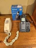 Panasonic cordless phone set with box alongside beige corded phone
