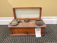 Front view of apothecary scale showing wood base, marble top with crack, brass pans, glass cover