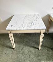 three-quarter view of wooden side table showing marble top and legs