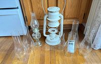 Group shot of Beacon lantern, oil lamp and six glass chimneys