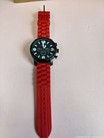 Front view of watch showing dial, bezel, red strap