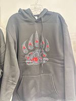 Full front view of black hoodie showing graphic and pocket