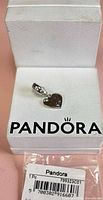 Front view of Pandora heart dangle charm on box showing bale with stones and SKU bag
