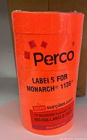 Front view of shrink-wrapped Perco fluorescent red label roll showing product branding and compatibility text