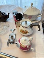 Group shot of tureen, teapots, juicer, corkscrew, enamel pot, boxed item