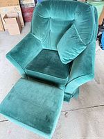 Front view of green velvet armchair with pillow and ottoman