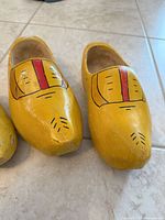 Adult pair of yellow wooden clogs, top view showing painted design and wear
