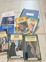 Assorted Canadian crime, disaster, weather paperbacks, North American Birds hardcover, blue spiral notebook