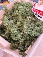 Bin containing tangled green artificial pine garland strands