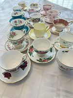 Fourteen assorted teacup and saucer sets arranged on table