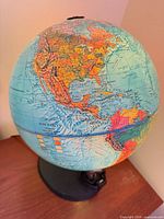 Front view of illuminated raised-relief globe on wood base