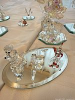 Multiple figurines including poodle, double rings, clown on oval mirrored base