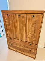 Front view showing two cabinet doors with recessed pulls above two wide drawers