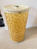 Full view of gold and ivory plastic laundry hamper