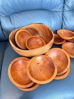 Large wooden bowl filled with several of the small bowls showing size relation and wood grain