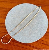 Full view of rope chain necklace laid out on round mat