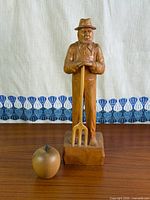 Front view of carved farmer figure with apple for scale