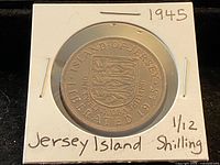 Obverse view of coin in cardboard flip showing Jersey coat of arms and handwritten year and denomination