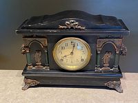 Front view of black Sessions mantel clock with ornate feet, columns, and dial