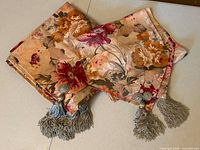 Tablecloth and table runner folded, tassels visible